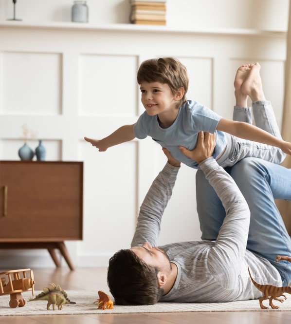 Joyful,Young,Man,Father,Lying,On,Carpet,Floor,,Lifting,Excited